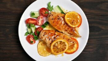 1. Introducción al Pollo a la Naranja al Horno El pollo a la naranja al horno es una receta deliciosa que combina la suavidad de la carne de pollo con el sabor fresco, dulce y ligeramente ácido de la naranja. Este plato es muy popular en muchas cocinas del mundo porque logra un equilibrio perfecto entre sabores naturales, aromas cítricos y una textura jugosa que se obtiene gracias a la cocción lenta en el horno. La naranja aporta un toque especial al pollo, creando una salsa natural que impregna cada pieza de carne con un sabor intenso y refrescante. Además, al cocinarse en el horno, el pollo adquiere una superficie dorada y ligeramente caramelizada, mientras que por dentro permanece tierno y jugoso. Esta receta es ideal para diferentes ocasiones. Puede servirse como plato principal en una comida familiar, en una cena especial o incluso en reuniones con amigos. Su preparación no es complicada y no requiere ingredientes difíciles de encontrar, lo que la convierte en una opción perfecta para quienes desean preparar un plato elegante sin pasar demasiado tiempo en la cocina. Otro aspecto destacado del pollo a la naranja al horno es su valor nutricional. El pollo es una fuente excelente de proteínas, mientras que la naranja aporta vitamina C, antioxidantes y un aroma natural que mejora el sabor del plato sin necesidad de usar demasiados condimentos artificiales. Además, esta receta se puede acompañar fácilmente con diferentes guarniciones como arroz blanco, puré de patatas, verduras asadas o ensalada fresca. Gracias a su versatilidad, el pollo a la naranja al horno se adapta a muchos estilos de cocina y preferencias gastronómicas. Si buscas una receta sabrosa, saludable y fácil de preparar, esta opción será una excelente elección. A continuación, veremos los ingredientes necesarios y el proceso paso a paso para preparar este delicioso plato. 2. Ingredientes para preparar Pollo a la Naranja al Horno Para preparar un delicioso pollo a la naranja al horno, es importante utilizar ingredientes frescos y de buena calidad. Esto garantizará un sabor más intenso y una mejor textura en el resultado final. Ingredientes principales 1 pollo entero troceado o 4 muslos de pollo 3 naranjas grandes y jugosas 3 dientes de ajo 1 cebolla mediana 2 cucharadas de miel 2 cucharadas de salsa de soja 3 cucharadas de aceite de oliva 1 cucharadita de pimienta negra 1 cucharadita de sal 1 cucharadita de pimentón dulce 1 ramita de romero o tomillo (opcional) Ingredientes opcionales para intensificar el sabor 1 cucharadita de jengibre rallado 1 cucharada de mostaza 1 cucharada de azúcar moreno ralladura de naranja Guarniciones recomendadas Aunque el pollo a la naranja al horno puede servirse solo, también combina muy bien con: arroz blanco patatas al horno verduras asadas ensalada fresca cous cous Estos acompañamientos ayudan a equilibrar el plato y permiten disfrutar mejor de la deliciosa salsa de naranja que se forma durante la cocción. 3. Preparación paso a paso del Pollo a la Naranja al Horno Preparar esta receta es bastante sencillo si se siguen los pasos correctamente. A continuación se explica el proceso completo para obtener un pollo jugoso y lleno de sabor. Paso 1: Preparar el horno Precalienta el horno a 180 °C durante unos 10 minutos antes de empezar la cocción. Esto permitirá que el pollo se cocine de manera uniforme desde el principio. Paso 2: Preparar la marinada de naranja Exprime el jugo de dos naranjas en un recipiente grande. Luego añade: la miel la salsa de soja el aceite de oliva el ajo picado la pimienta el pimentón dulce el jengibre (opcional) Mezcla todos los ingredientes hasta obtener una salsa homogénea. Esta marinada será la base del sabor del plato. Paso 3: Marinar el pollo Coloca las piezas de pollo en un recipiente grande o en una bolsa de cocina. Vierte la marinada sobre el pollo y asegúrate de que todas las piezas queden bien cubiertas. Para lograr un sabor más intenso, deja marinar el pollo durante 30 minutos a 2 horas en el refrigerador. Cuanto más tiempo repose, mejor absorberá los sabores. Paso 4: Preparar la bandeja de horno Corta la cebolla en rodajas y colócala en el fondo de una bandeja para horno. Esto ayudará a aromatizar el pollo durante la cocción. Coloca las piezas de pollo encima de la cebolla y vierte parte de la marinada restante sobre ellas. Corta la tercera naranja en rodajas y distribúyelas alrededor del pollo. Paso 5: Hornear el pollo Introduce la bandeja en el horno precalentado y cocina durante 40 a 50 minutos. A mitad de la cocción, abre el horno y utiliza una cuchara para rociar el pollo con la salsa que se está formando en la bandeja. Esto ayudará a mantener la carne jugosa y a intensificar el sabor. Si deseas que el pollo tenga una piel más dorada, puedes aumentar la temperatura a 200 °C durante los últimos 10 minutos de cocción. Paso 6: Comprobar la cocción El pollo estará listo cuando la carne esté bien cocida y la superficie tenga un color dorado. Si al pinchar la carne sale un jugo claro, significa que está perfectamente cocido. Una vez listo, retira la bandeja del horno y deja reposar el pollo durante unos 5 minutos antes de servir. 4. Consejos para disfrutar mejor el Pollo a la Naranja al Horno Para disfrutar al máximo de esta receta, es recomendable tener en cuenta algunos consejos que mejorarán la experiencia gastronómica. Usar naranjas frescas El sabor del plato depende en gran parte del jugo de naranja. Por eso, es mejor utilizar naranjas naturales recién exprimidas en lugar de jugo procesado. No cocinar el pollo demasiado tiempo Si el pollo permanece demasiado tiempo en el horno, puede volverse seco. Lo ideal es controlar la cocción y retirar el pollo cuando esté dorado y jugoso. Aprovechar la salsa La salsa que queda en la bandeja es muy sabrosa. Puedes usarla para: rociar el pollo al servir mezclar con arroz acompañar patatas o verduras Añadir hierbas aromáticas Hierbas como el romero, tomillo o perejil pueden aportar un aroma extra al plato y hacerlo aún más apetitoso. Servir inmediatamente El pollo a la naranja al horno se disfruta mucho más cuando está recién hecho. Servirlo caliente permite apreciar mejor la textura jugosa del pollo y el aroma cítrico de la salsa. Conclusión El pollo a la naranja al horno es una receta sencilla, deliciosa y perfecta para cualquier ocasión. Gracias a la combinación del pollo con el jugo natural de naranja, este plato logra un sabor equilibrado entre dulce, ácido y salado que resulta irresistible. Además, su preparación es fácil y no requiere técnicas complicadas, por lo que cualquier persona puede cocinarlo en casa con excelentes resultados. Con ingredientes simples y un proceso claro, es posible preparar un plato que parece digno de un restaurante. Si te gusta experimentar con recetas de pollo llenas de sabor, el pollo a la naranja al horno es definitivamente una opción que vale la pena probar. Una vez que lo prepares, seguramente se convertirá en una de tus recetas favoritas para compartir con familia y amigos.